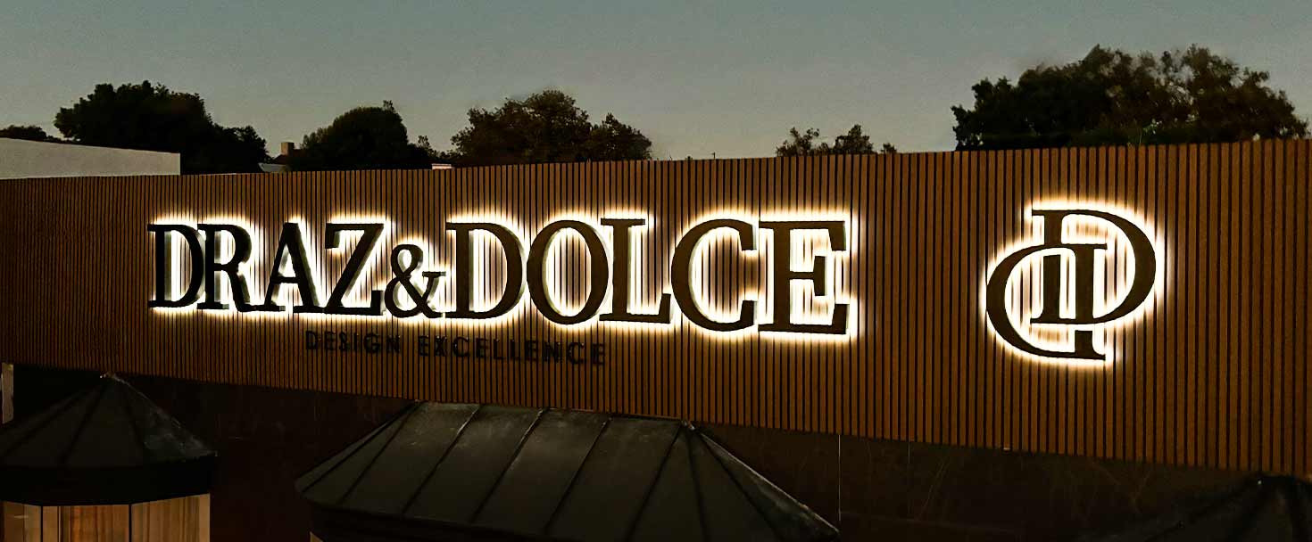 Draz & Dolce illuminated channel letters on a storefront wooden panel