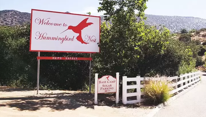 Outdoor pylon sign for Hummingbird Nest with red lettering and white background