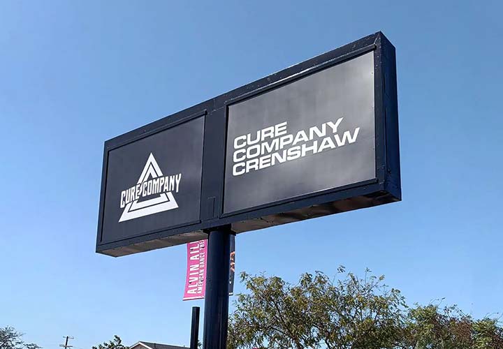 Outdoor pylon sign for Cure Company showcasing the company name and logo on a black background