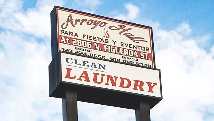 Outdoor pylon sign for Arroyo Hall featuring contact information in red on a white background