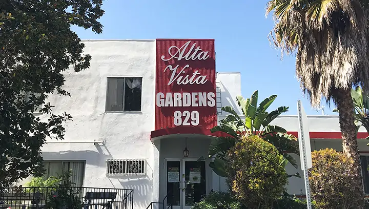 Building outdoor signage reading brand name and address for Alta Vista on red background