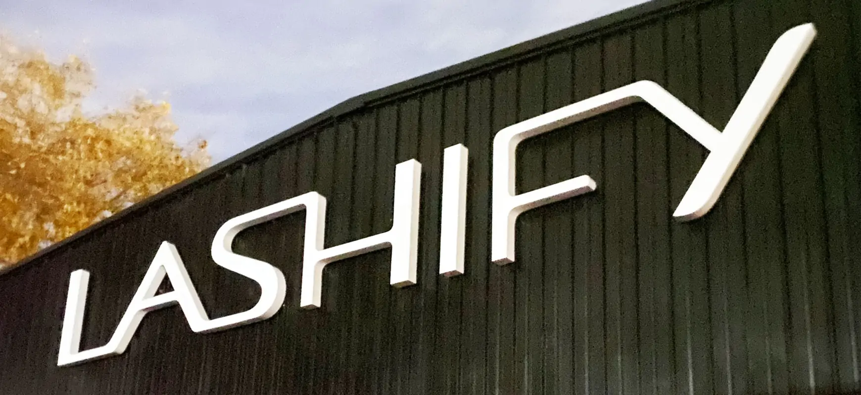 Custom outdoor signage fixed on building facade and reading brand name for Lashify in white