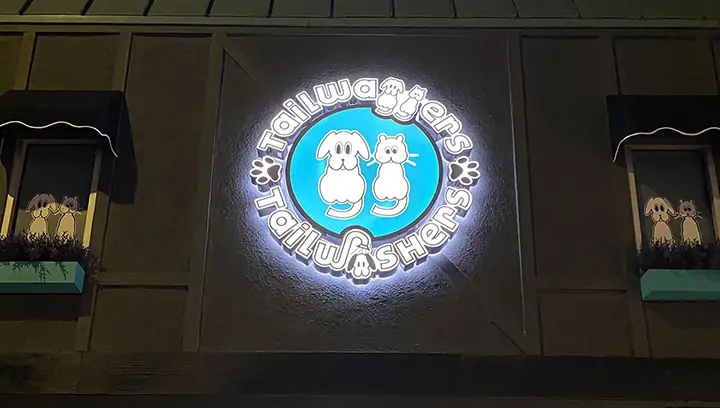 Illuminated outdoor signage fixed on the building and displaying brand logo for Tailwaggers