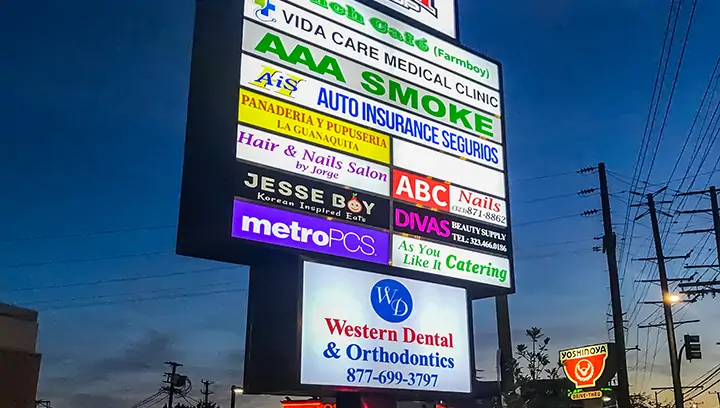 Promotional outdoor signage with illumination showcasing different logos for several businesses