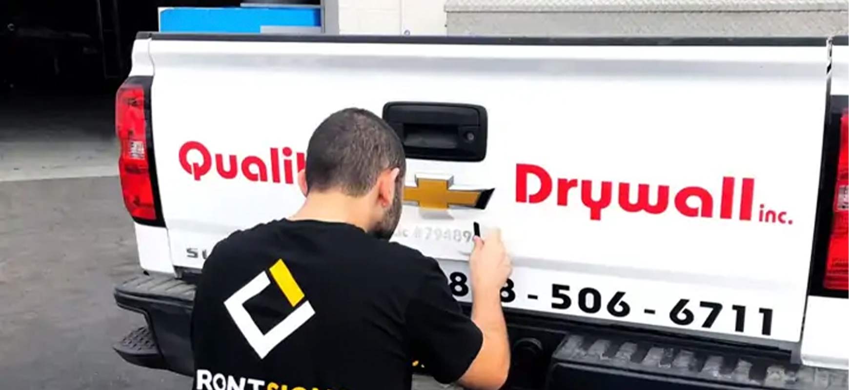 Car branding installation process for Quality Drywall Inc with vinyl being applied on the rear