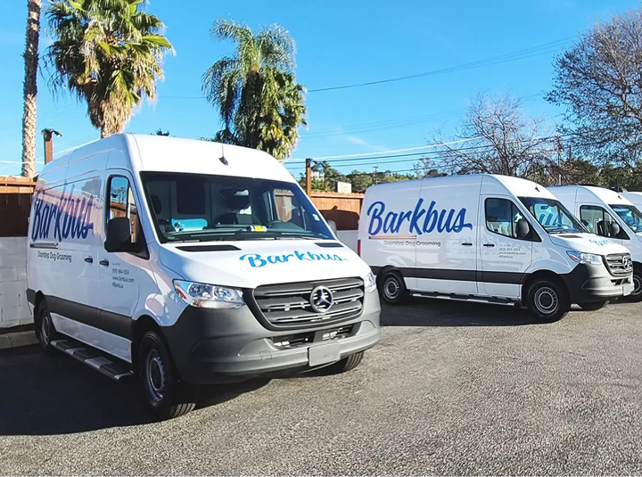 Fleet vehicle branding for Barkbus showcasing the brand logo on front and sides of the vans