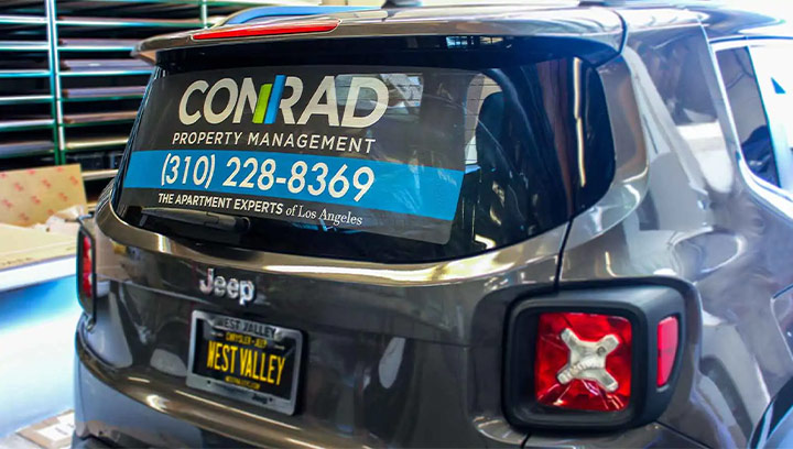 Perforated car branding for Conrad Property Management featuring the brand logo and contact number