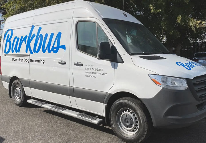 Vehicle branding for Barkbus showcasing the brand name and logo in bright blue on a van