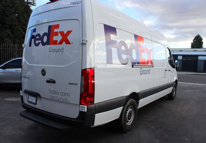 Vehicle branding for FedEx in bold lettering displaying the company name and logo on van